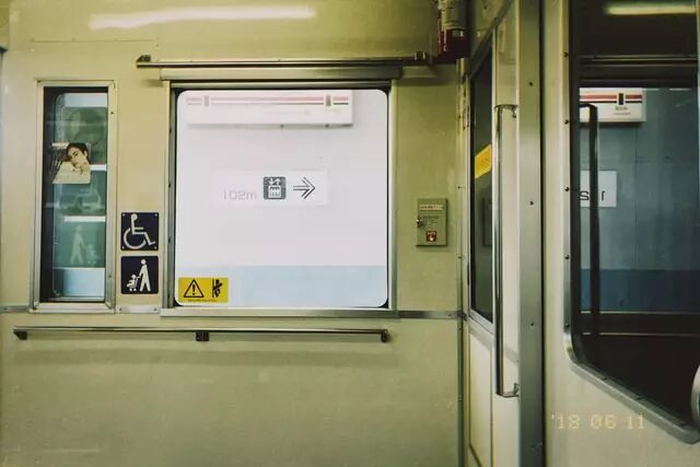 Interior view of a public transit carriage showing accessibility signage and a windowed door.