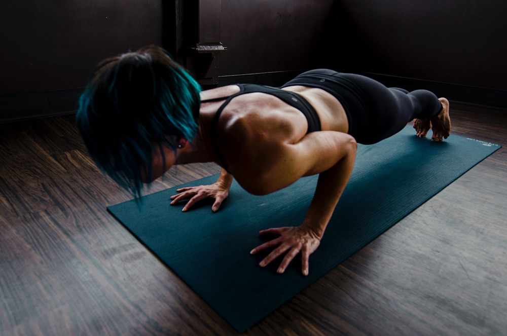 A woman does push-ups on an exercise mat.