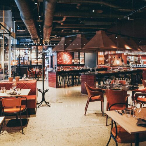 Spacious modern restaurant interior with warm lighting and red furniture.